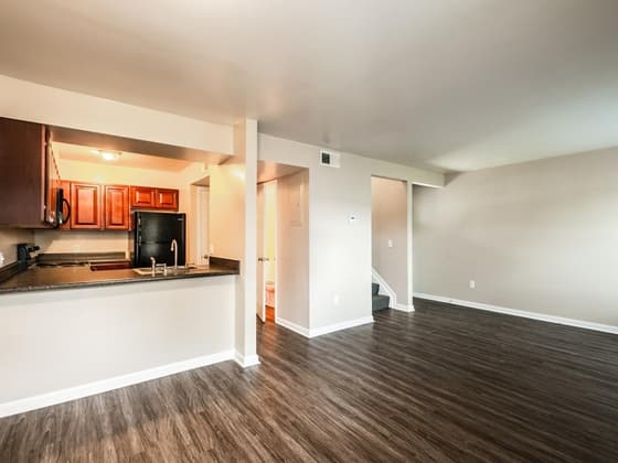 An empty living room with vinyl plank flooring and a pass-through to the kitchen