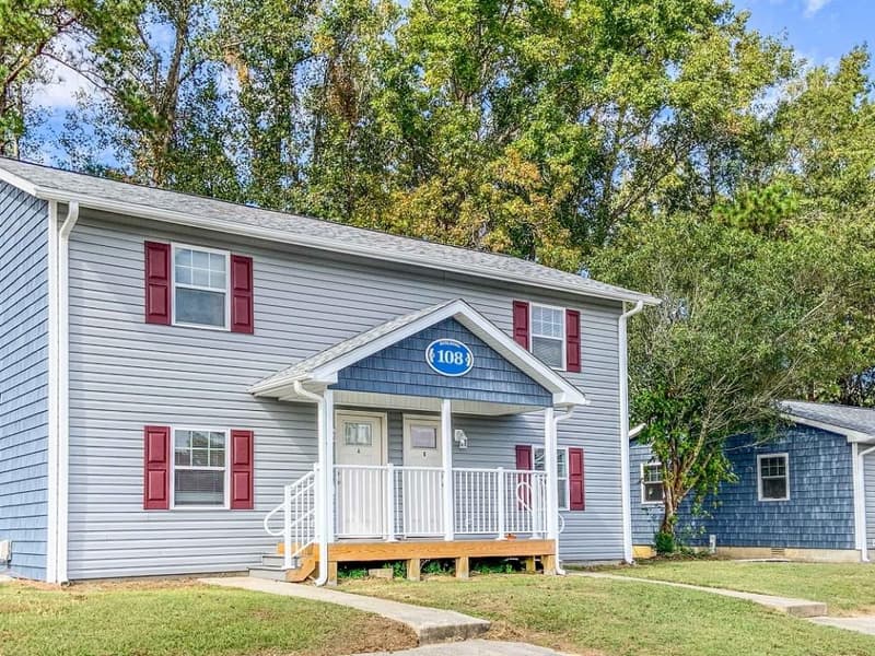 A ground-floor door and porch, blue siding with red shutters